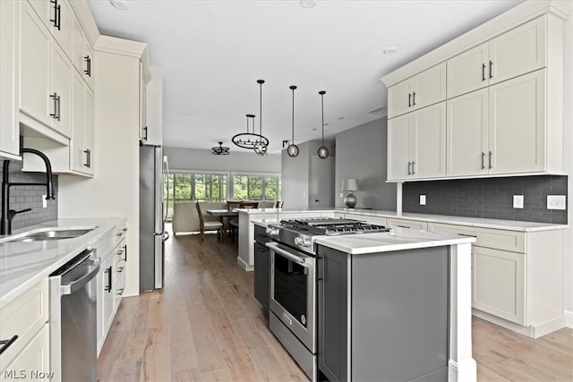 kitchen with kitchen peninsula, appliances with stainless steel finishes, sink, pendant lighting, and a center island