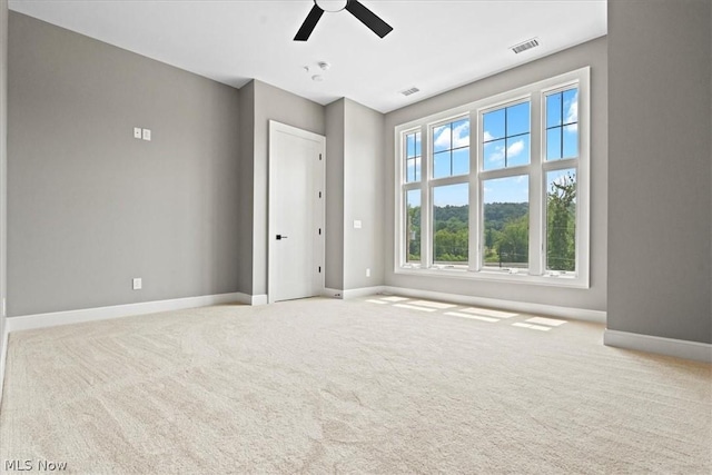 empty room featuring ceiling fan and light carpet