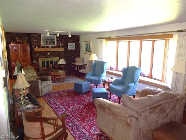 11421 Clay Rd, Newton, WV 25266 - living room with track lighting, a brick fireplace, and wood finished floors
