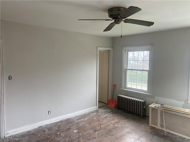 spare room featuring wood-type flooring, ceiling fan, and radiator