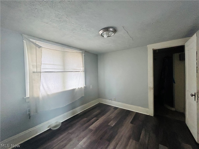 spare room featuring dark hardwood / wood-style floors and a textured ceiling