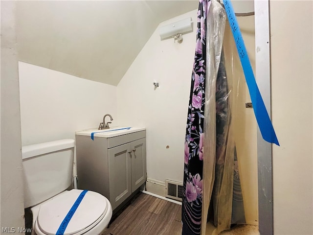 bathroom featuring hardwood / wood-style floors, lofted ceiling, vanity, and toilet