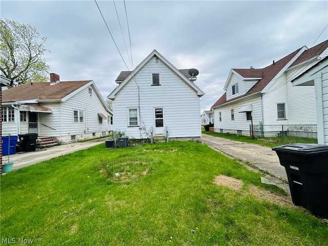 back of house featuring central AC and a lawn