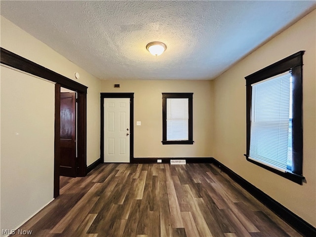 unfurnished room with dark hardwood / wood-style floors and a textured ceiling