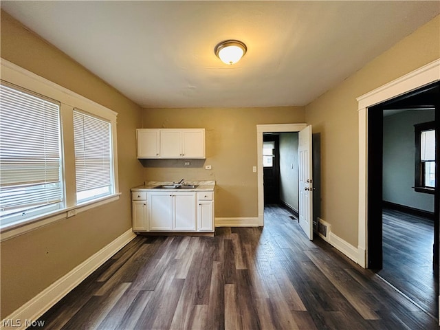 kitchen with dark wood-type flooring, white cabinetry, and sink