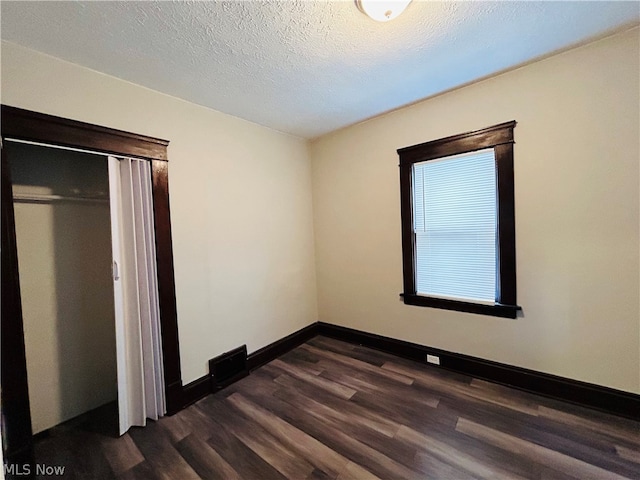 unfurnished bedroom featuring dark wood-type flooring, a closet, and a textured ceiling