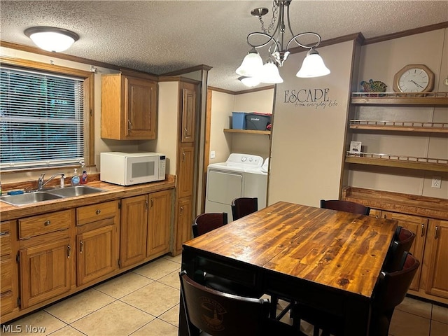 kitchen with sink, butcher block countertops, a textured ceiling, decorative light fixtures, and ornamental molding