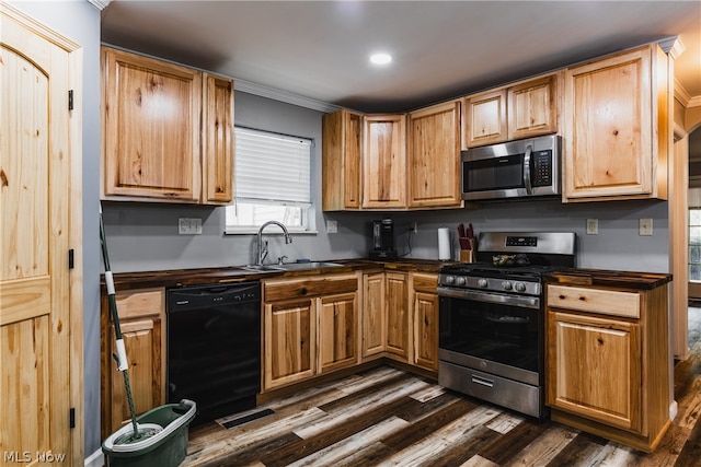 kitchen featuring sink, crown molding, stainless steel appliances, and dark wood-type flooring