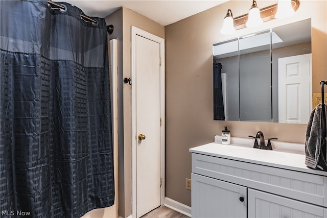 bathroom with vanity with extensive cabinet space and hardwood / wood-style flooring