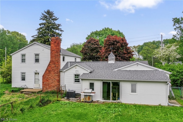 rear view of property with a yard and central AC unit