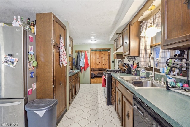 kitchen with appliances with stainless steel finishes, a textured ceiling, sink, light tile flooring, and pendant lighting