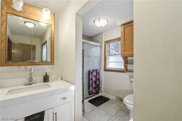 bathroom featuring tile flooring, vanity, toilet, and a textured ceiling