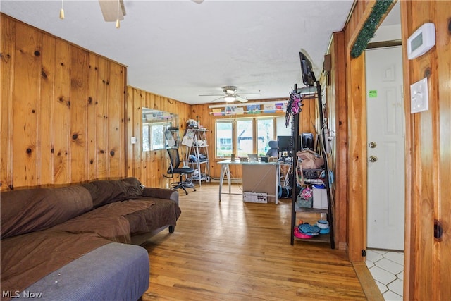 living room featuring wood walls, ceiling fan, and light hardwood / wood-style floors