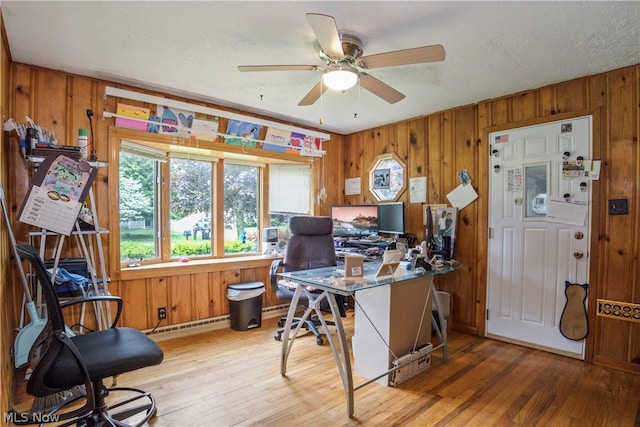 office with ceiling fan, light wood-type flooring, wood walls, and a textured ceiling