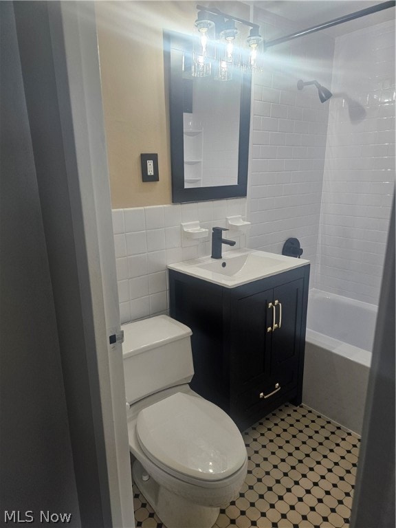 full bathroom featuring tiled shower / bath combo, vanity, tile walls, backsplash, and toilet