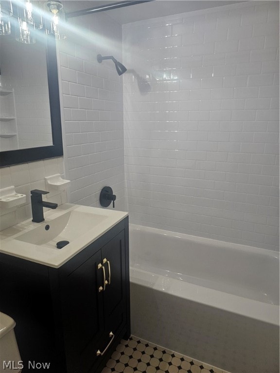 full bathroom featuring tile flooring, tiled shower / bath, vanity, and tile walls