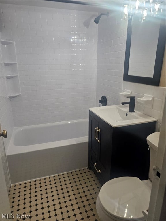 full bathroom featuring tiled shower / bath, tile walls, tile floors, toilet, and vanity