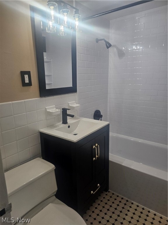 full bathroom with tiled shower / bath, vanity, tile walls, backsplash, and toilet