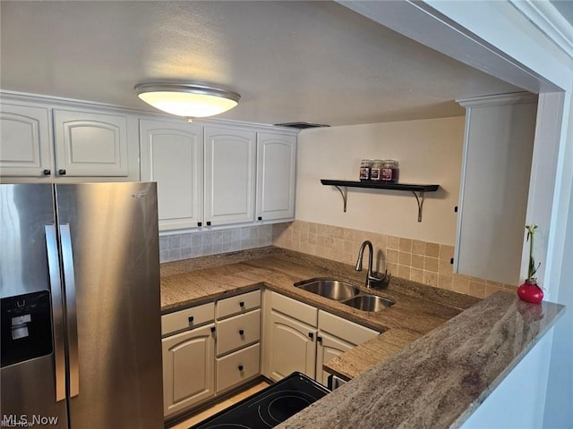 kitchen with range, white cabinetry, backsplash, sink, and stainless steel fridge