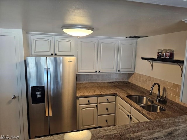 kitchen featuring backsplash, sink, white cabinets, and stainless steel fridge