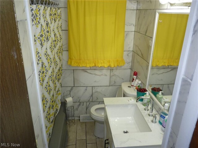 full bathroom with tile patterned floors, vanity, tile walls, and toilet