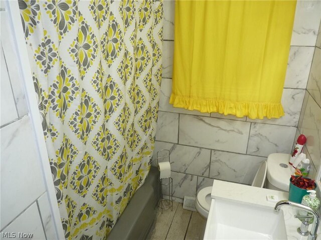 full bathroom featuring tile walls, shower / bath combination with curtain, toilet, and sink