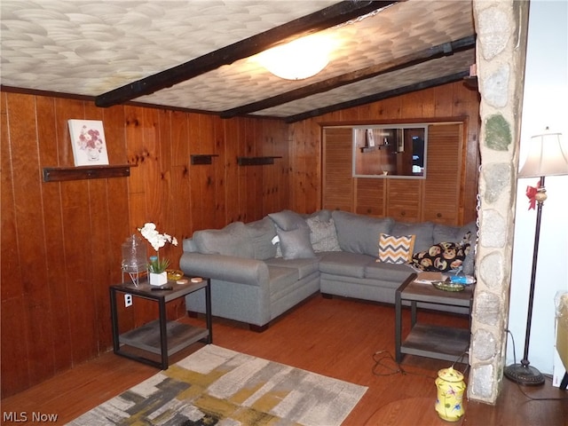 living room with wood walls, lofted ceiling with beams, and hardwood / wood-style floors