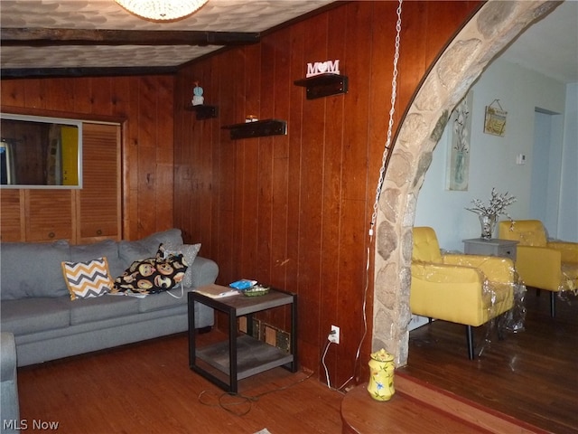 living room with vaulted ceiling with beams, dark wood-type flooring, and wood walls