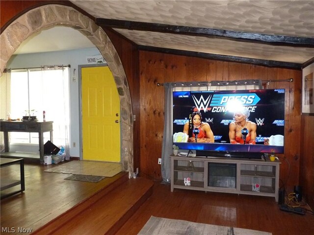 living room with beam ceiling, hardwood / wood-style flooring, and wooden walls