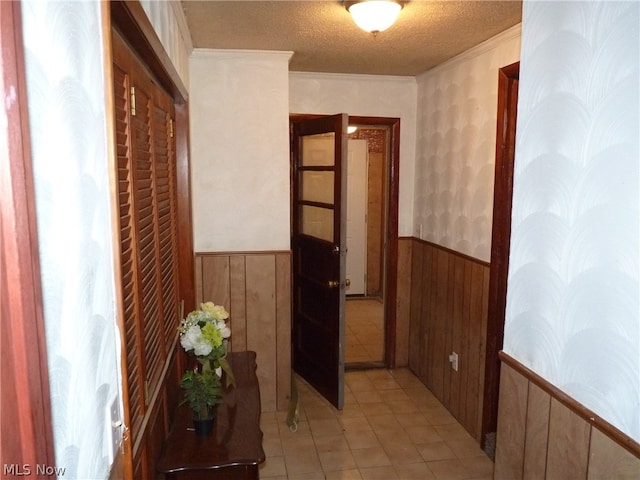 corridor featuring a textured ceiling, light tile patterned floors, and crown molding