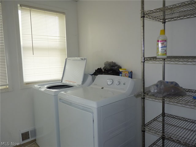 laundry room with washing machine and clothes dryer and a wealth of natural light