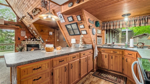 kitchen featuring wood walls, a fireplace, sink, light hardwood / wood-style floors, and lofted ceiling