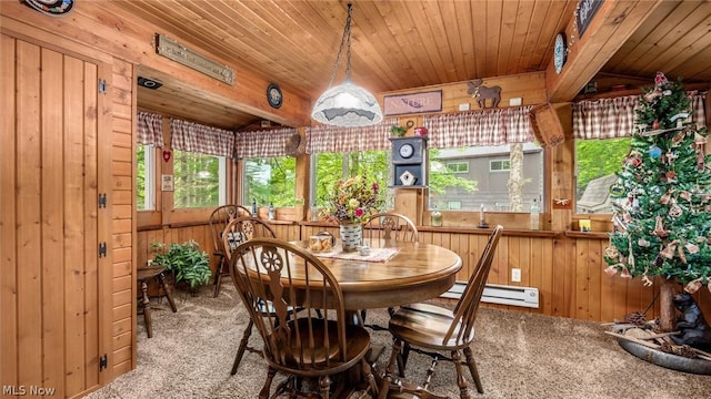 carpeted dining area with wooden ceiling, a baseboard radiator, and wooden walls