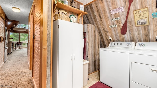 washroom featuring washing machine and clothes dryer, wood walls, and light carpet