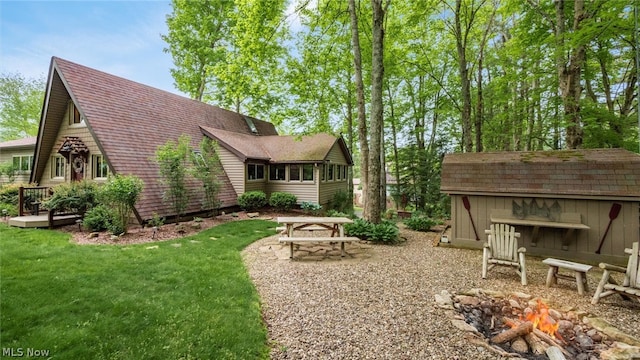 rear view of house featuring a yard, an outdoor fire pit, and an outdoor structure