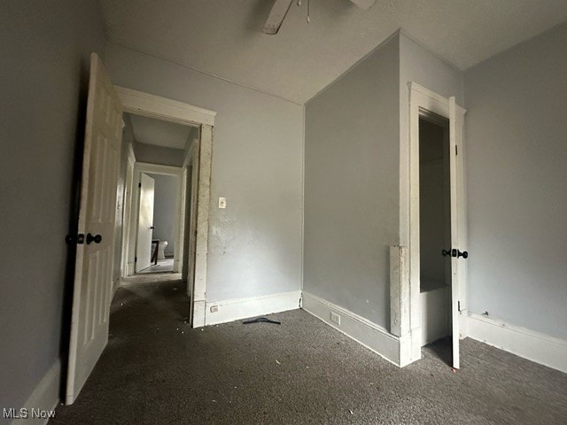 interior space with ceiling fan and dark carpet