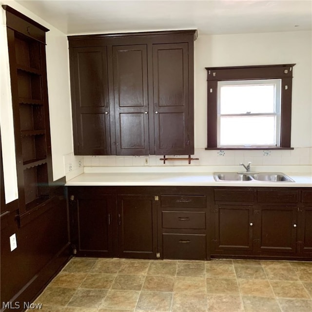 kitchen with dark brown cabinets, sink, and light tile flooring