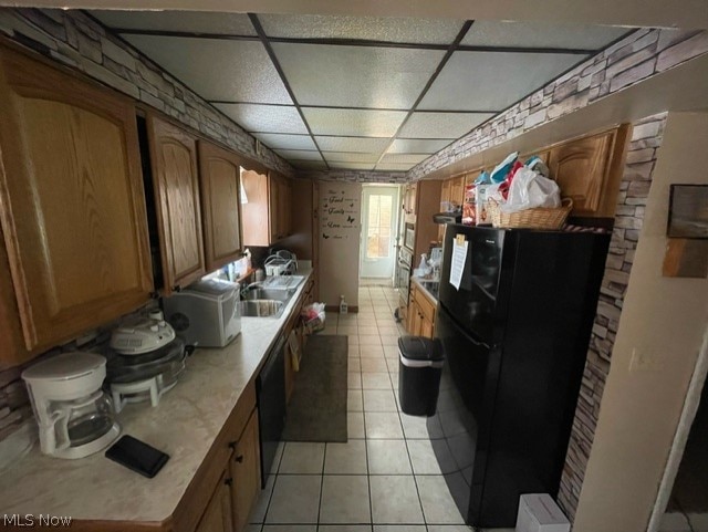 kitchen featuring a paneled ceiling, light tile floors, and black appliances