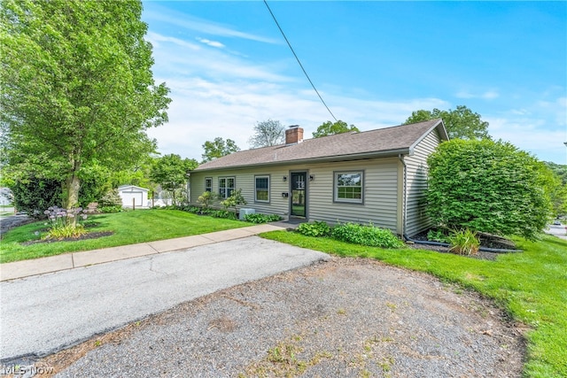 single story home with a front lawn and a storage unit