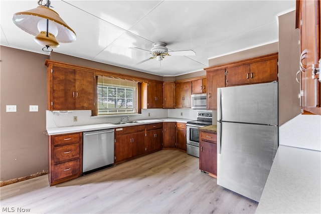 kitchen featuring stainless steel appliances, sink, ceiling fan, pendant lighting, and light hardwood / wood-style flooring