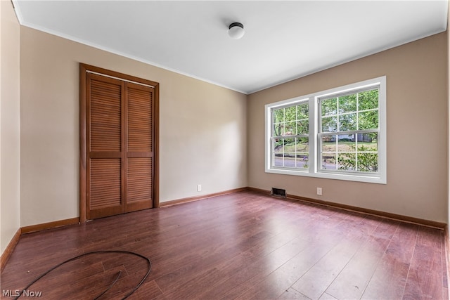 unfurnished bedroom featuring ornamental molding, hardwood / wood-style flooring, and a closet