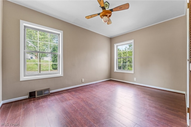 spare room featuring hardwood / wood-style floors, ceiling fan, and a healthy amount of sunlight