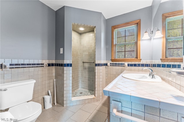 bathroom featuring toilet, tile patterned floors, a shower with door, tile walls, and vanity