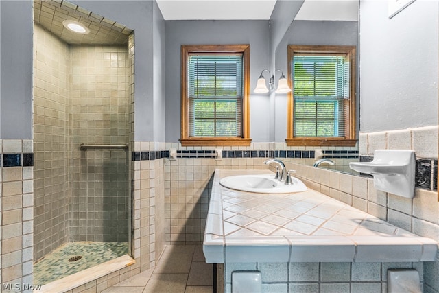 bathroom featuring tiled shower, vanity, tile walls, and a healthy amount of sunlight