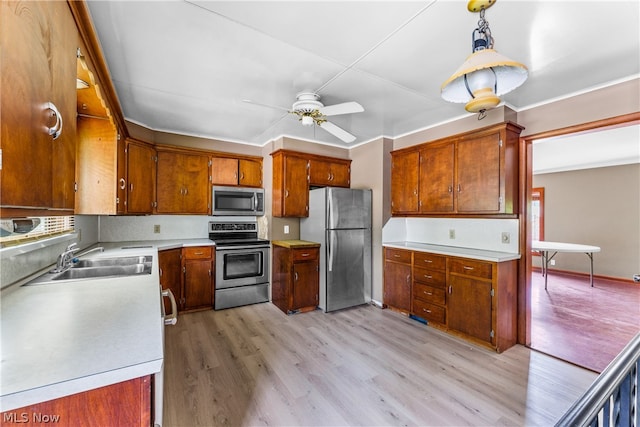 kitchen with stainless steel appliances, decorative light fixtures, sink, light hardwood / wood-style floors, and ceiling fan