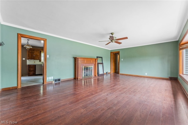 unfurnished living room with dark wood-type flooring, crown molding, and a brick fireplace