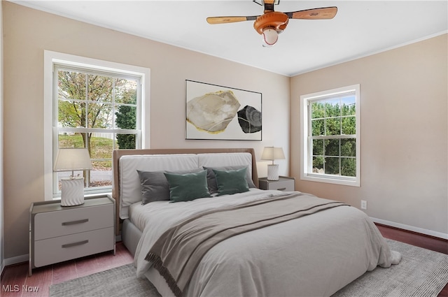 bedroom with dark hardwood / wood-style flooring, multiple windows, and ceiling fan