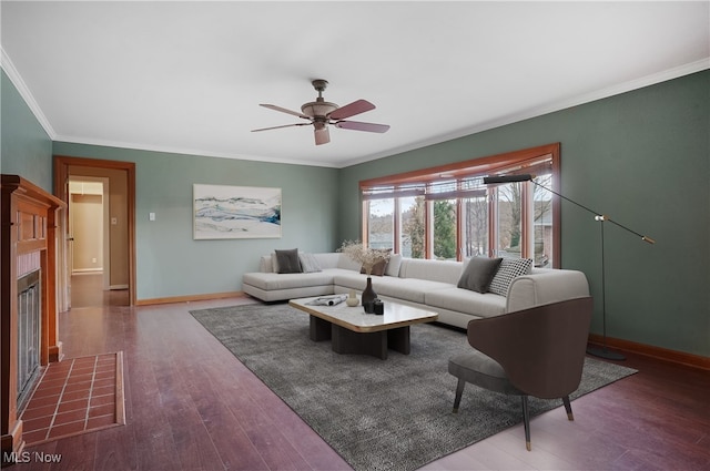 living room featuring ceiling fan, wood-type flooring, a fireplace, and crown molding