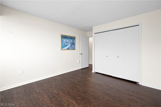 unfurnished bedroom with dark hardwood / wood-style floors and a closet