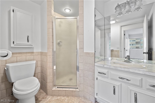 bathroom featuring tile floors, a shower with shower door, tile walls, vanity with extensive cabinet space, and toilet